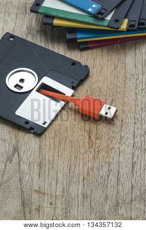 Used floppy diskettes with orange USB cable Plug on wooden backgrounddesign for technology concept