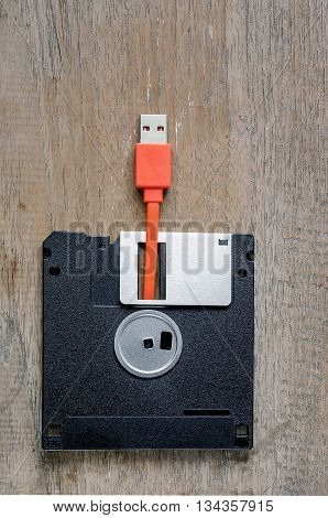 Used floppy diskettes with orange USB cable Plug on wooden backgrounddesign for technology concept