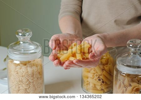 Handful of pasta. Woman cooking. Thre Glass Jar With Raw Pasta. Woman is going to cook pasta.