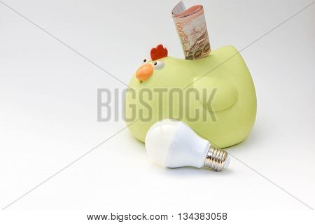 LED bulb and yellow chicken piggy bank on white background - Saving Technology