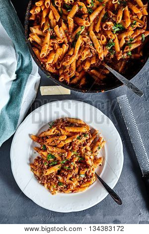 Top view of american chop suey - pasta dish with beef, tomato sauce, mozarella cheese, spices and parsley. Italian-American cuisine