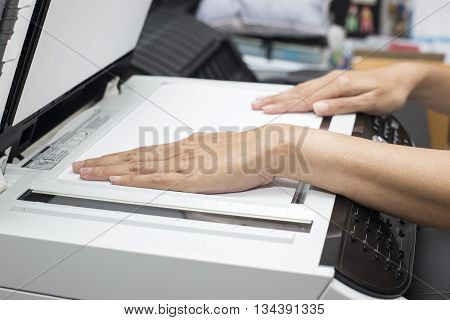 woman hands putting a sheet of paper into a copying device