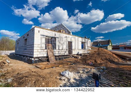 The building is under construction with roofing and the materials for construction