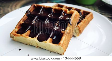 Vienna Waffles with chocolate topping. Aged photo. Delicious dessert. White plate with Chocolate covered Wafers. Toned. Delicious dessert. Wide photo for wallpaper or site slider.
