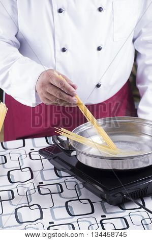 Chef putting spaghetti to boiled in the pan / cooking spaghetti concept