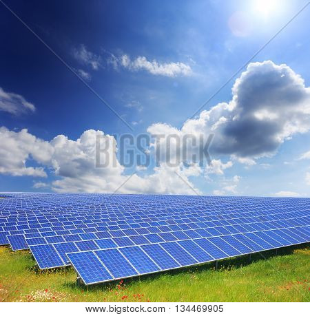 Solar panels with green field and clody sky