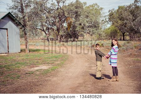 Brother and sister walking down a dirt track in outback Australia
