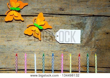 Colorful Felty Butterflies And Candles With A Sign On Wooden Table