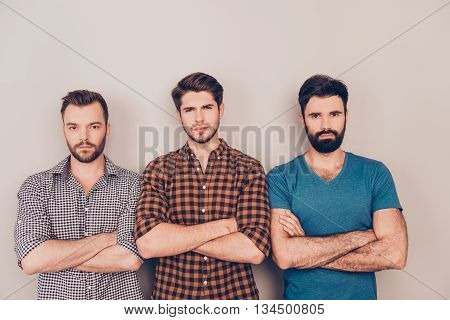 Three Handsome Serious Men Cross Hands While Standing  Gray Background