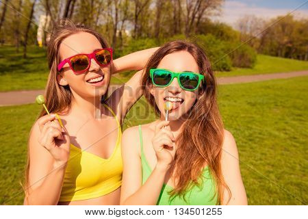 Happy Cheerful Girlfriends In Glasses Licking Chupa Chups