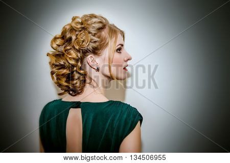 Beautiful girl in profile with lush hair in green dress.