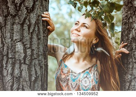 Young beautiful happy woman looking at the sky through the trees.