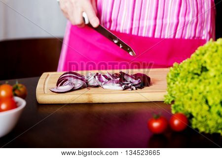 Woman cut red onion on cutting board