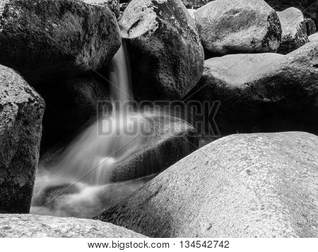 Blurred river stream detail of wild rocky mountain river. Silky effect. Motion rendition effect. Slow shutter speed effect. Long exposure effect. . Black and white image.