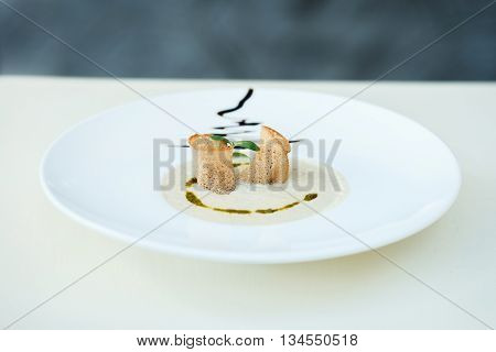 bowl of vegetarian mushroom puree soup in a large plate on bokeh background of greens