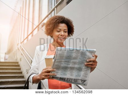 business and people concept - young smiling african american businesswoman with coffee cup going down stairs into city underpass