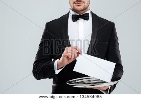 Closeup of waiter in tuxedo with bowtie holding blank card on tray