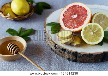 Grapefruit lemons and ginger on a wooden stand with a plate of honey