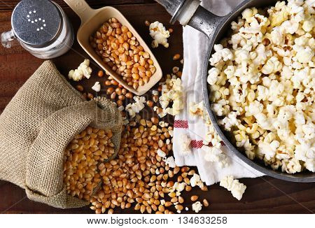 Top view of a pot full of freshly popped popcorn with salt and unpopped kernels on the side. 