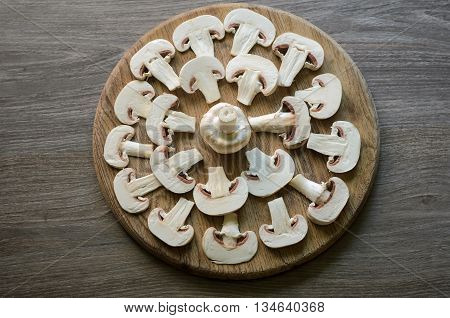 Cut champignons settled into geometrical patterns on a wooden background