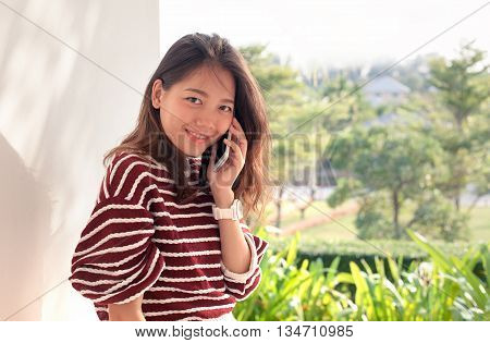 younger asian woman talking on smart phone with happiness emtion