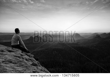 Man Sit On Peak. Colorful Mist And Fog In Forest Valley Bellow.