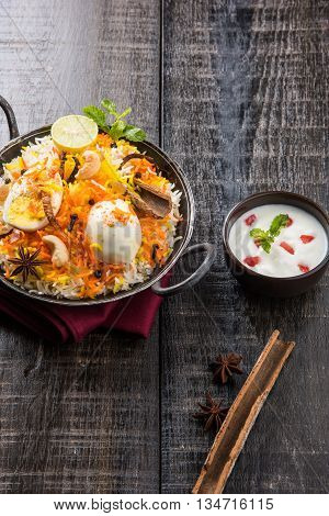 Basmati rice slowly cooked with Masala roasted egg and spices served in kadhai or kadai with yogurt dip, selective focus, egg biryani or anda rice or egg rice