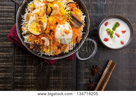 Basmati rice slowly cooked with Masala roasted egg and spices served in kadhai or kadai with yogurt dip, selective focus, egg biryani or anda rice or egg rice