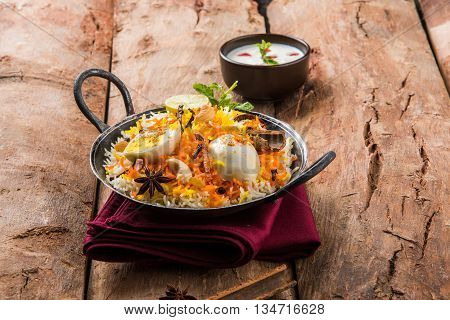 Basmati rice slowly cooked with Masala roasted egg and spices served in kadhai or kadai with yogurt dip, selective focus, egg biryani or anda rice or egg rice
