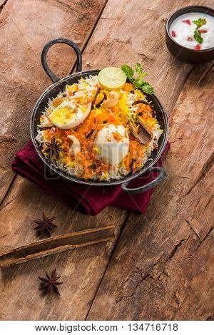 Basmati rice slowly cooked with Masala roasted egg and spices served in kadhai or kadai with yogurt dip, selective focus, egg biryani or anda rice or egg rice