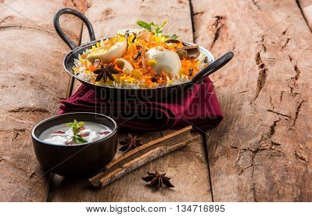 Basmati rice slowly cooked with Masala roasted egg and spices served in kadhai or kadai with yogurt dip, selective focus, egg biryani or anda rice or egg rice