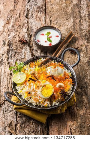 Basmati rice slowly cooked with Masala roasted egg and spices served in kadhai or kadai with yogurt dip, selective focus, egg biryani or anda rice or egg rice