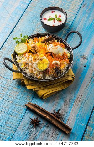 Basmati rice slowly cooked with Masala roasted egg and spices served in kadhai or kadai with yogurt dip, selective focus, egg biryani or anda rice or egg rice