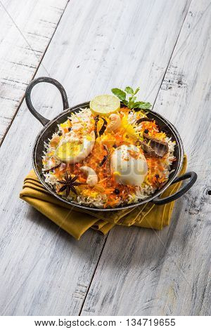 Basmati rice slowly cooked with Masala roasted egg and spices served in kadhai or kadai with yogurt dip, selective focus, egg biryani or anda rice or egg rice