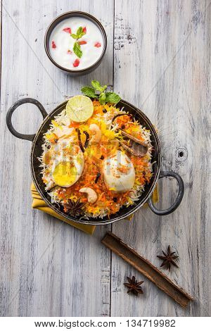 Basmati rice slowly cooked with Masala roasted egg and spices served in kadhai or kadai with yogurt dip, selective focus, egg biryani or anda rice or egg rice