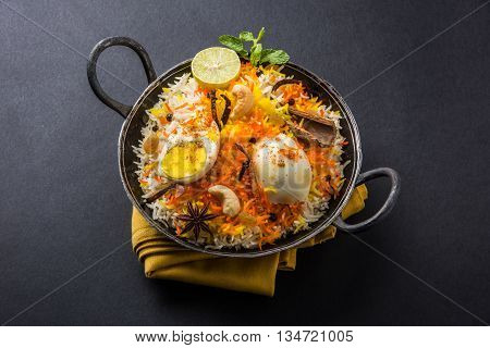 Basmati rice slowly cooked with Masala roasted egg and spices served in kadhai or kadai with yogurt dip, selective focus, egg biryani or anda rice or egg rice