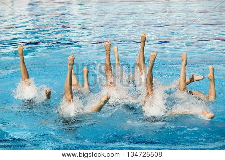 Synchronized swimmers legs movement. Synchronized swimming team performing a synchronized routine of elaborate moves in the water.