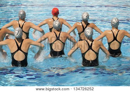 Synchronized swimming team performing a synchronized routine of elaborate moves in the water