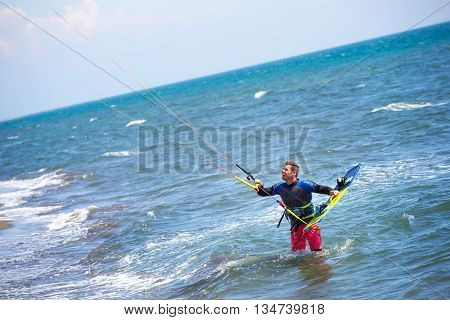 Athletic man riding on kite surf board on a sea waves