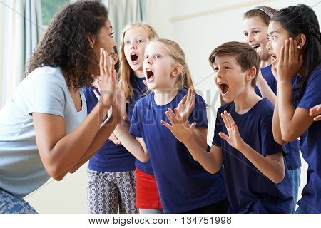 Group Of Children With Teacher Enjoying Drama Class Together