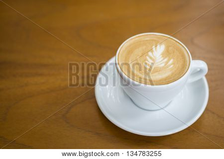 Hot art cappuccino cup on wood background