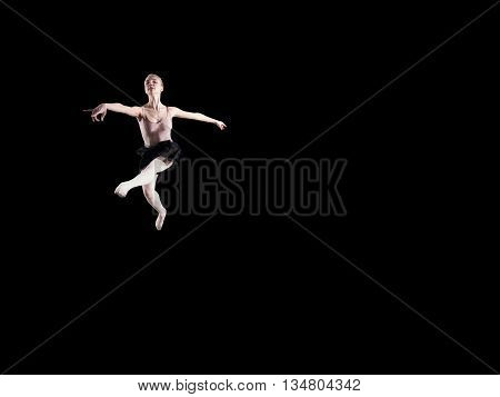 Young beautiful ballerina on a black background in studio