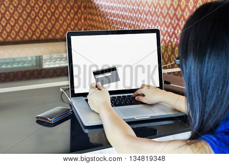 Women hands hold credit or debit card infront of blank screen notebook or laptop for internet working or oline shopping