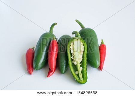 Bright green jalapeno hot peppers and birdseye chilli peppers on white background