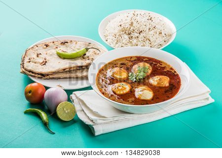 egg curry with roti/chapati and jeera rice, tasty and spicy anda curry with roti and rice, indian egg masala curry served in ceramic bowl with roti, salad and jeera rice
