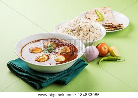 egg curry with roti/chapati and jeera rice, tasty and spicy anda curry with roti and rice, indian egg masala curry served in ceramic bowl with roti, salad and jeera rice