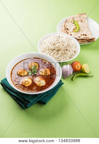 egg curry with roti/chapati and jeera rice, tasty and spicy anda curry with roti and rice, indian egg masala curry served in ceramic bowl with roti, salad and jeera rice