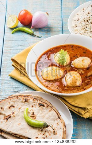 egg curry with roti/chapati and jeera rice, tasty and spicy anda curry with roti and rice, indian egg masala curry served in ceramic bowl with roti, salad and jeera rice