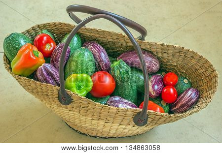 Wicker shopping bag filled with fresh vegetables from the market. Fresh zucchini eggplant tomatoes and peppers.