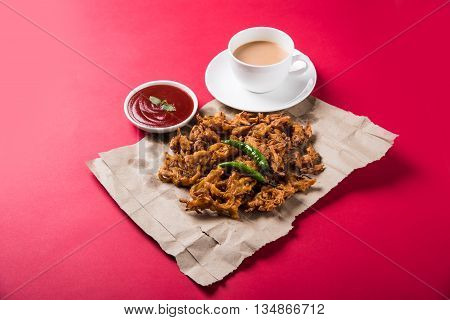 Crispy onion bhaji or kanda bhaji or fried onion pakore or pakode, delicious street food, favourite indian snack in monsoon served with hot tea
